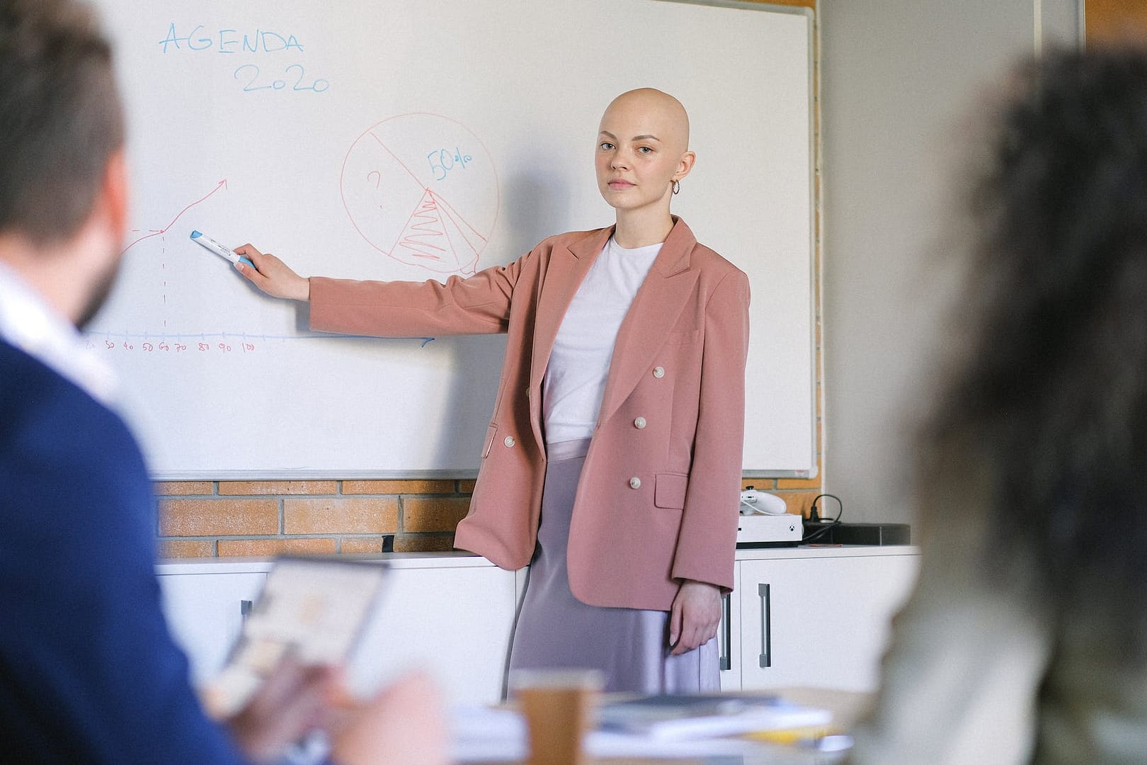 bald woman near whiteboard with charts